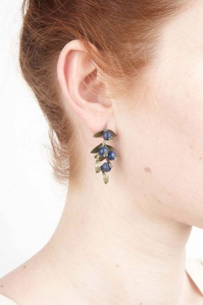 Die Ohrstecker bestehen aus einem hängenden Blaubeer-Zweig mit je acht Blättern handpatinierter Bronze und vier reifen Blaubeeren aus dunkelblauem Aventurin. Die Blätter und Beeren verteilen sich harmonisch auf der gesamten Länge.